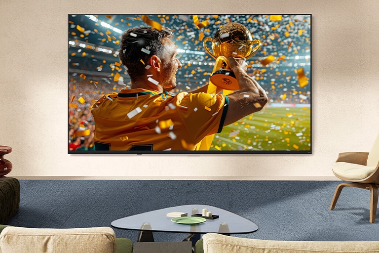 LG NANO 4K UHD AI NU85 Ultra Big TV, pritvirtintas prie gyvenamojo kambario sienos, rodo didelio mastelio sporto pergalės sceną su konfeti ir iškelta taure, pabrėžiant ryškias spalvas, raiškumą ir įtraukiantį mastelį.