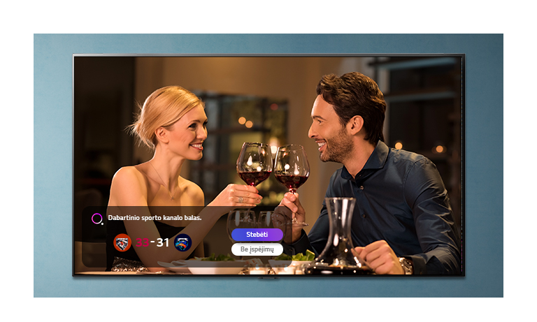 TV ekrane rodomas taurėmis susidaužiantys vyras ir moteris, tuo metu rodomas su sportu susijęs įspėjimas