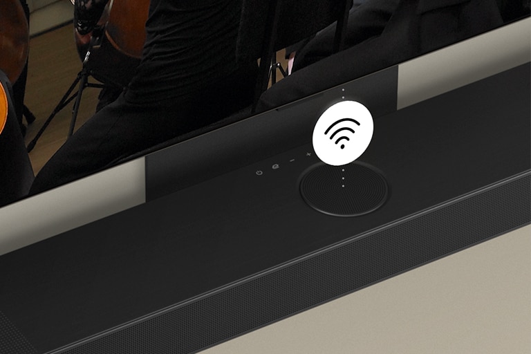 Prie sienos pritvirtintas LG OLED TV ir garso juosta su baltu „Wi-Fi“ simboliu viduryje.