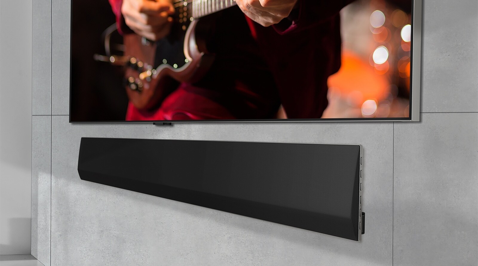Ant sienos sumontuoto LG OLED TV ir LG Soundbar apatinės dalies vaizdas iš arti, kampu.