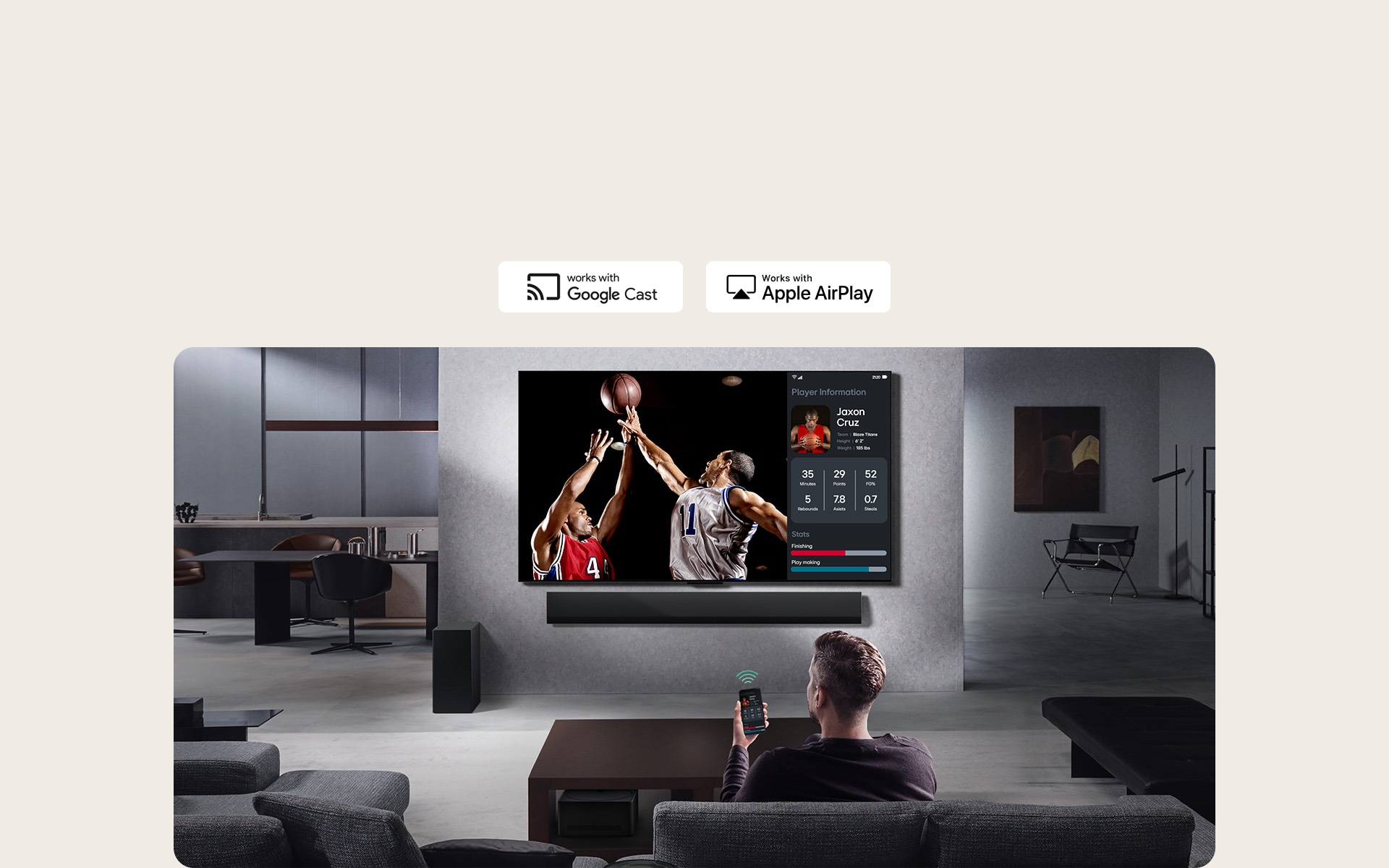 Person in their living room holding their phone. On the phone is a transmitting icon showing that the phone screen is being mirrored on the TV. On the TV is a basketball game to the side is the mirrored screen, showing player statistics. 