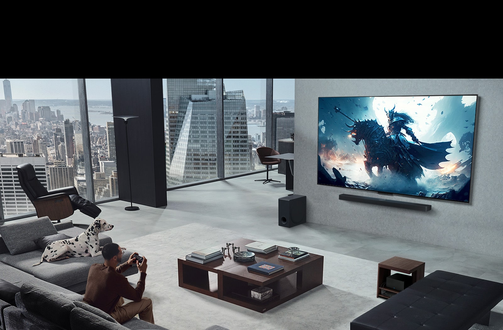 Kambarys, kuriame žmogus žaidžia vaizdo žaidimą per ant sienos sumontuotą „LG True Wireless TV“ ir klausosi per „LG Soundbar“ garso sistemą. Rankoje jis laiko valdiklį, tačiau žaidimų konsolės iš pirmo žvilgsnio nematyti. Taip pat nematyti jokių laidų. „Zero Connect Box“ paslėptas ir vos matomas po staliuku. 