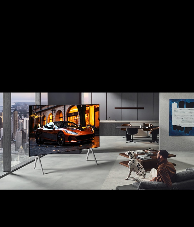 Svetainė su ant stovo esančiu „LG True Wireless TV“. „Zero Connect Box“ vos matomas po staliuku prie sofos – tai reiškia, kad jį galima lengvai padėti bet kurioje vietoje. Visas svetainės planavimas yra vizualiai švarus ir tvarkingas. 