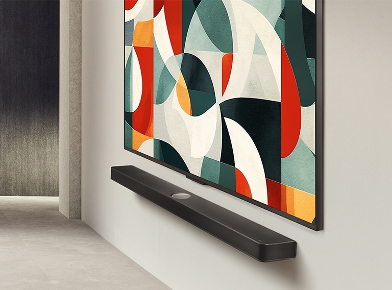 LG QNED TV televizoriaus vaizdas šiek tiek kampu, sumontuoto ant sienos virš „LG Soundbar“ garso sistemos šiuolaikiškoje svetainėje. LG QNED TV televizoriuje rodomas abstraktus žalios, baltos, raudonos ir oranžinės spalvų fonas.