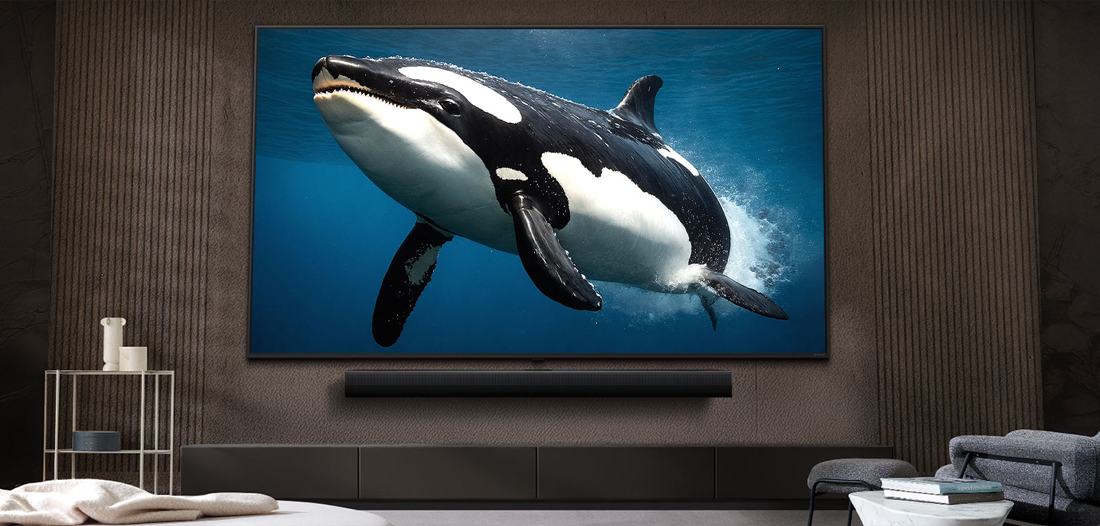 LG TV televizorius su įspūdingo dydžio ekranu, sumontuotas ant sienos virš LG Soundbar sistemos šiuolaikiško stiliaus svetainėje.