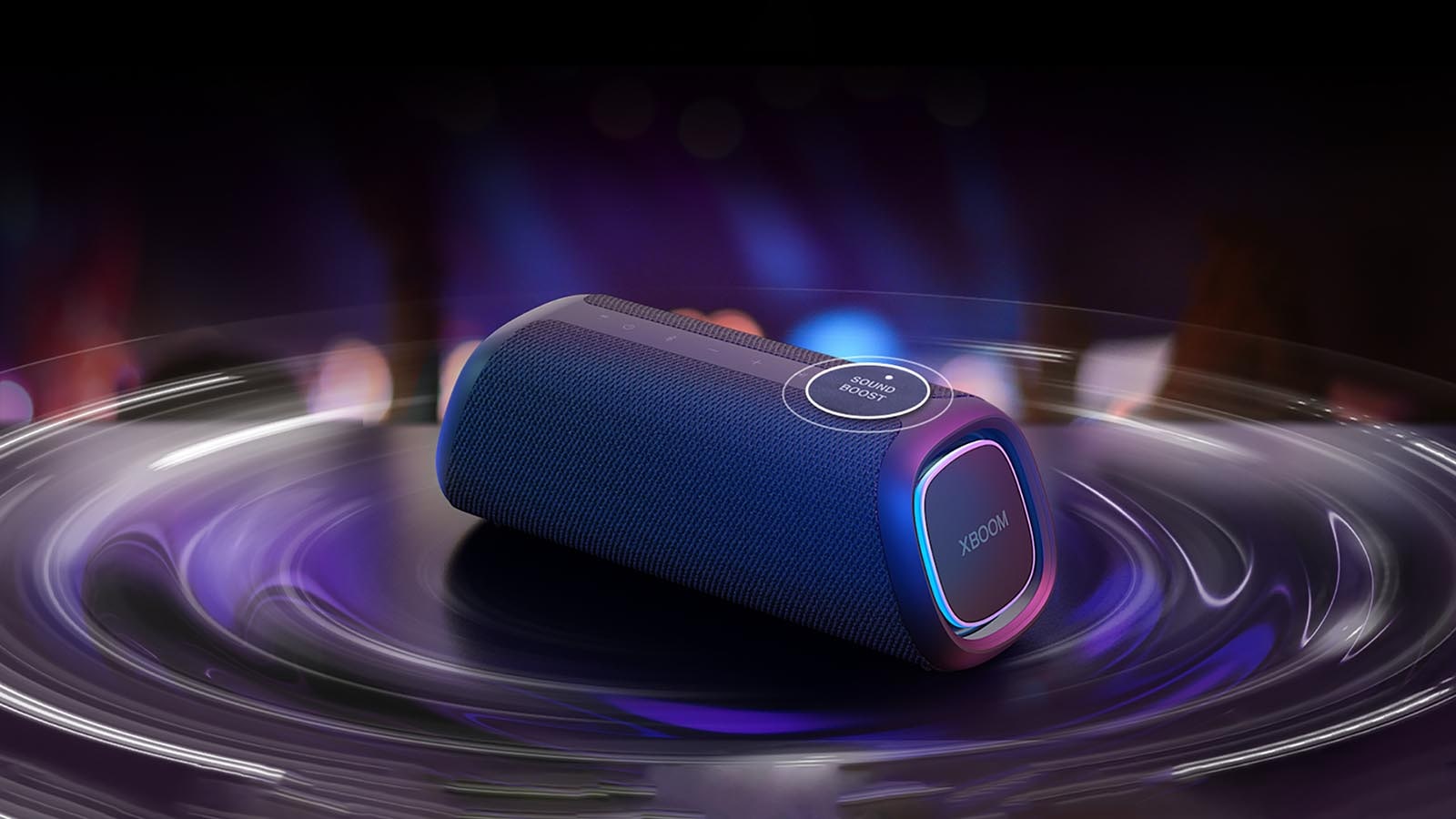 LG XBOOM GO XG7 pastatytas ant stalo. Mygtukas „Sound Boost“ yra padidintas, o garso bangų efektai yra po garsiakalbiu. Paleisti vaizdo įrašą.