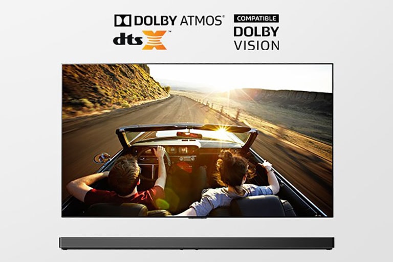 Bendras TV ir gulsčiojo garsiakalbio vaizdas. Televizoriuje rodoma atvirame automobilyje keliu į saulėlydį važiuojanti pora.