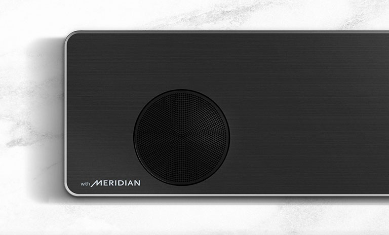 LG gulsčiojo garsiakalbio su „Meridian“ logotipu apatiniame kairiajame kampe kairės pusės vaizdas stambiu planu.
