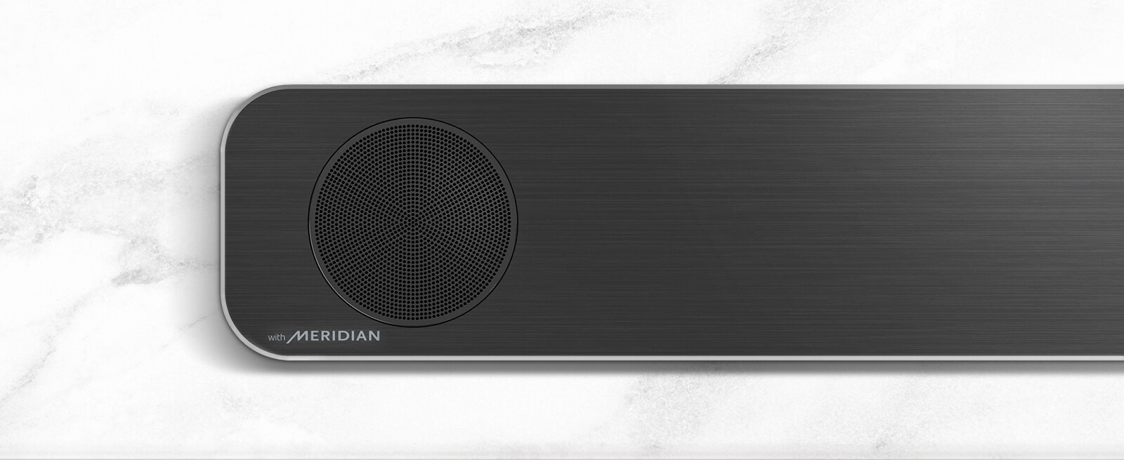 LG gulsčiojo garsiakalbio su „Meridian“ logotipu apatiniame kairiajame kampe kairės pusės vaizdas stambiu planu.