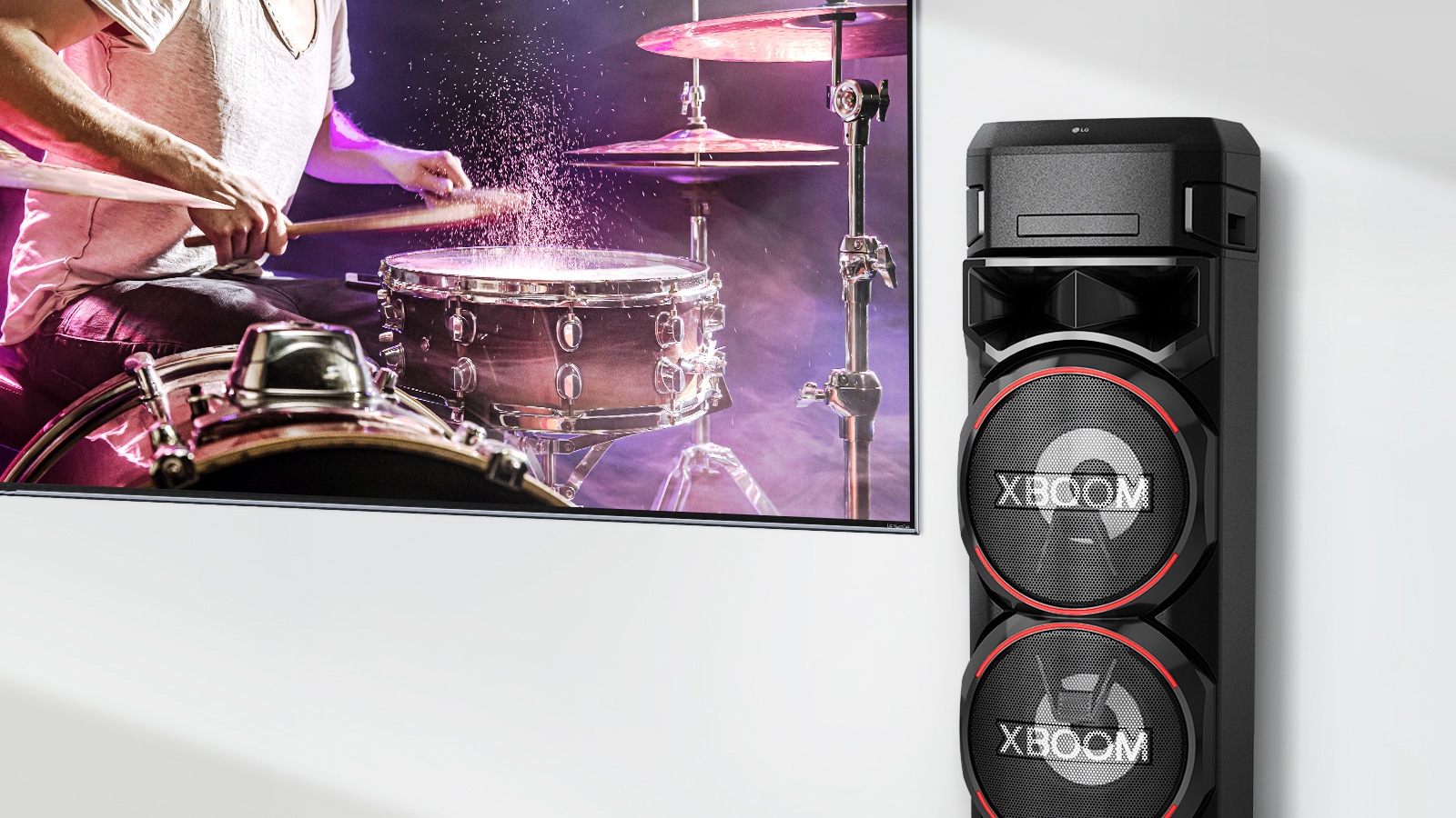 Ant sienos įrengtas TV, o LG XBOOM pastatytas jo dešinėje pusėje.