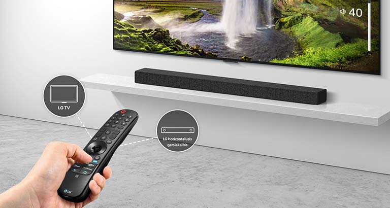 Žmogaus rankoje yra pultelis, kuriuo valdomas fone esantis televizorius ir horizontalusis garsiakalbis. Taip pat nurodytos LG televizoriaus ir LG horizontaliojo garsiakalbio piktogramos.