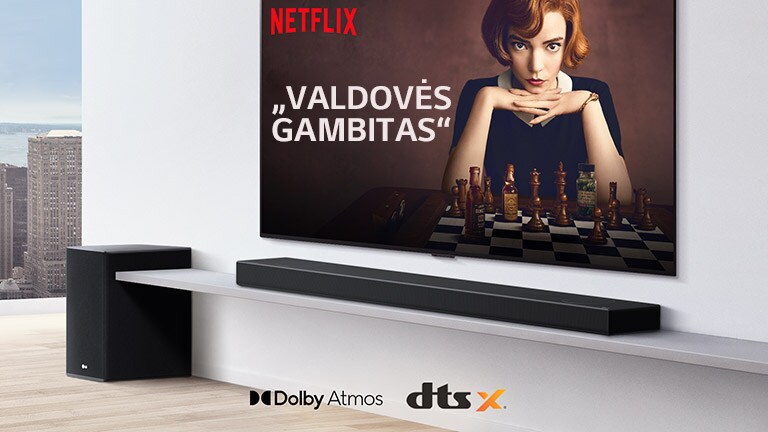 Ant sienos įrengtas televizorius. Televizoriaus ekrane rodomas TV laidos plakatas. LG Soundbars yra tiesiai po televizoriumi ant baltos lentynos, o šalia yra žemadažnis garsiakalbis. Paveikslėlio apatinėje vidurinėje dalyje yra „Dolby Atmos“ ir DTS:X logotipai.