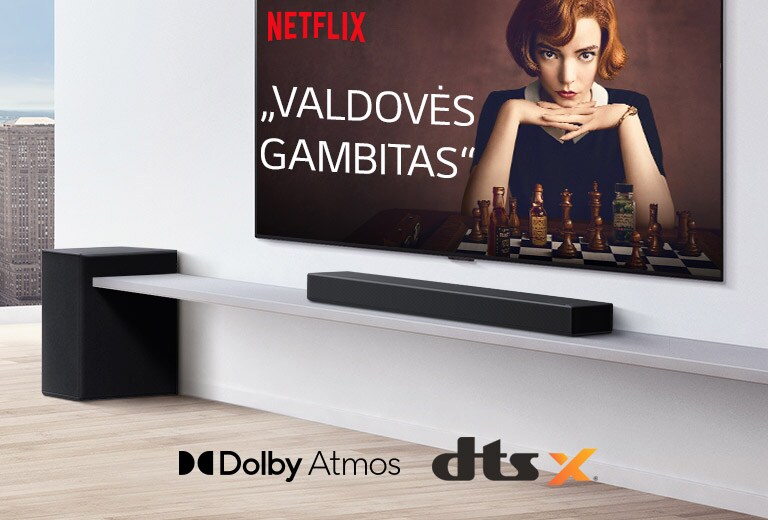 Ant sienos įrengtas televizorius. Televizoriaus ekrane rodomas TV laidos plakatas. LG Soundbars yra tiesiai po televizoriumi ant baltos lentynos, o šalia yra žemadažnis garsiakalbis. Paveikslėlio apatinėje vidurinėje dalyje yra „Dolby Atmos“ ir DTS:X logotipai.