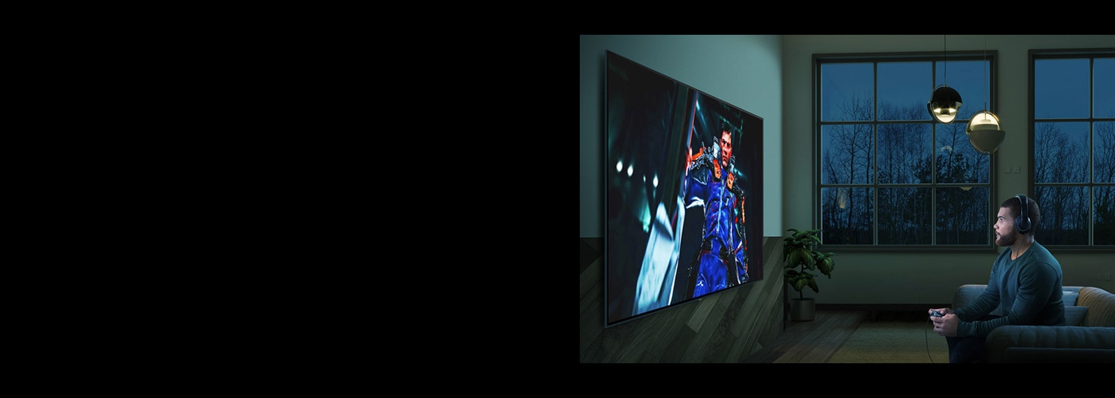 Vyras tamsiame kambaryje sėdi ant sofos priešais didelį TV ekraną ir žaidžia veiksmo žaidimą.