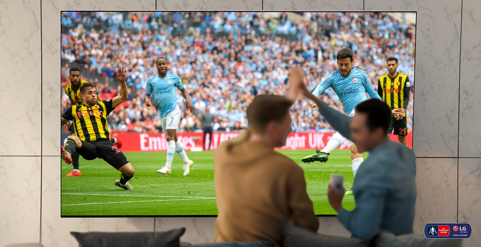 Du vyrai svetainėje žiūri futbolo rungtynes „Nanocell“ TV ir serga už komandą. Po juo pavaizduota technologija „NanoCell“, kuri pagerina vaizdo kokybę.