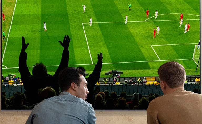 Dviejų vyrų svetainėje žiūrinčių futbolo rungtynes per „Nanocell“ TV vaizdas iš nugaros.