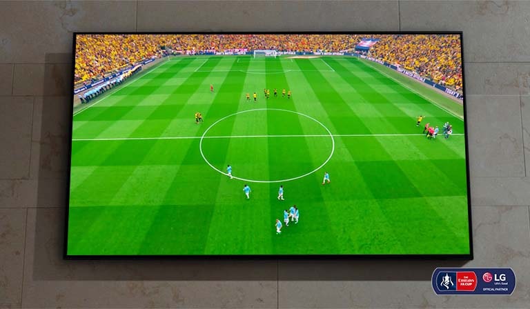 Ant sienos įrengtas „Nanocell“ TV. Ekrane rodoma futbolo rungtynių pradžia.