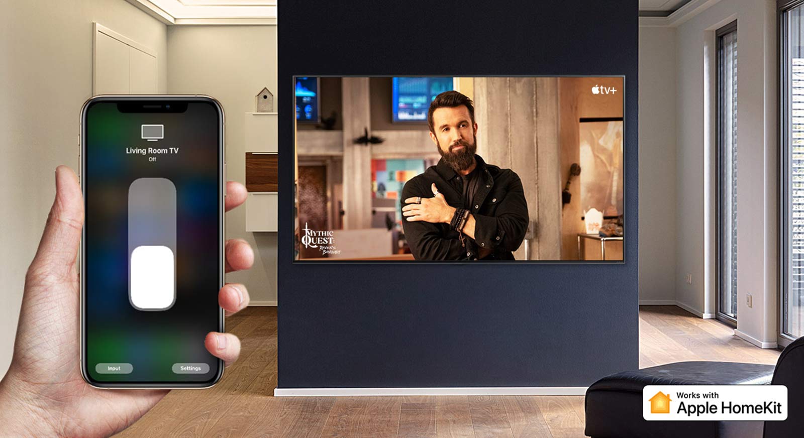 Televizorių „iPhone“ įrenginiu valdanti ranka stambiu planu ir televizorius, kuriame rodomas „Apple TV+“ turinys