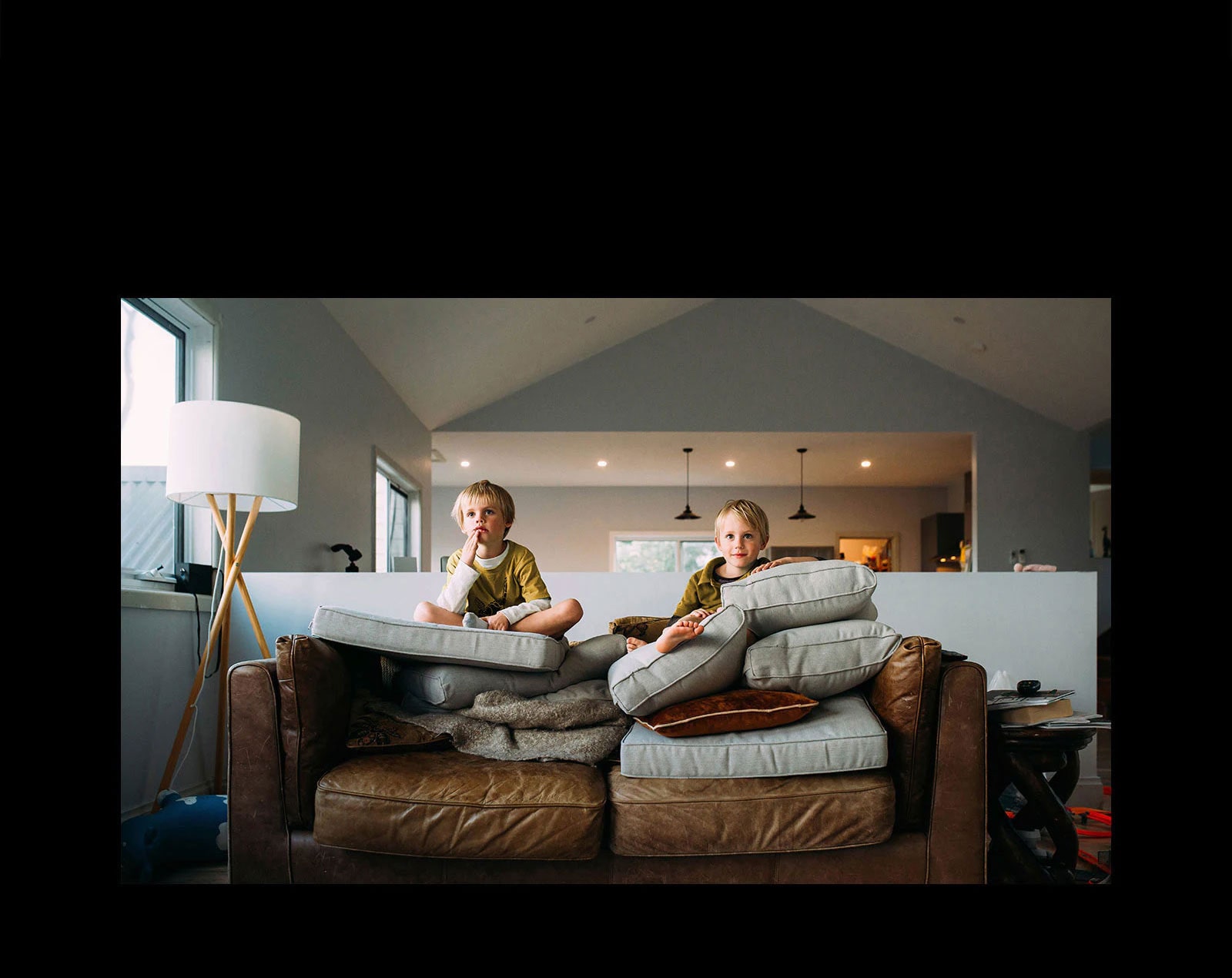 Ant sofos sėdintys dvyniai kažką žiūri per televizorių.