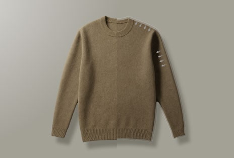 Vaizdo įrašas, kuriame matomas rudos spalvos megztinis, nesusitraukęs po džiovinimo, ir vyras, patenkintas drabužių audinio tekstūra.