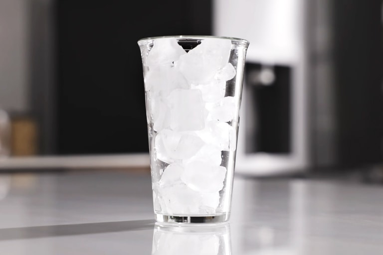 Skaidri stiklinė, pripildyta kvadratinių ledo kubelių iš LG šaldytuvo