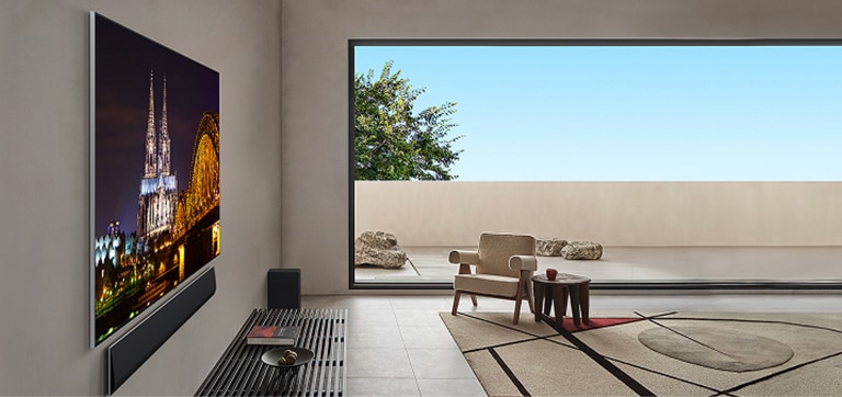 Svetainė su sieniniu LG OLED G5 TV ir LG „Soundbar“ garso kolonėle iš šono. Šis kampas pabrėžia „One Wall“ dizainą ir tai, kaip rėmeliai yra visiškai prigludę prie sienos. 