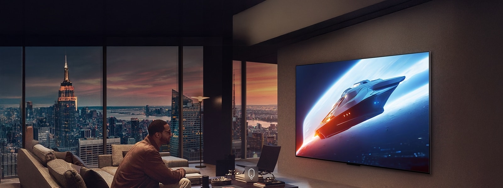 Elegantiška svetainė mansardos bute. Pro langą matomas gražus miesto peizažas. Vyras sėdi ant sofos ir žiūri turinį wall-mounted TV. 