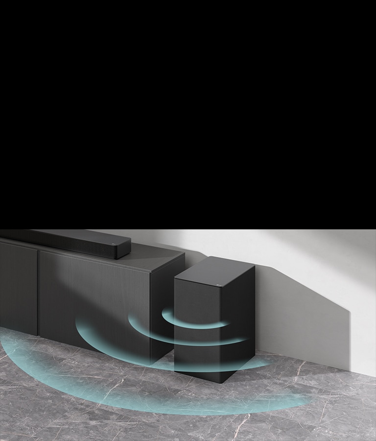 Ant spintelės pastatytas horizontalusis garsiakalbis („sound bar“). Šalia belaidis žemųjų dažnių garsiakalbis, padėtas ant grindų. Iš žemųjų dažnių garsiakalbio sklinda mėlyni garsą vaizduojantys grafiniai vaizdai.