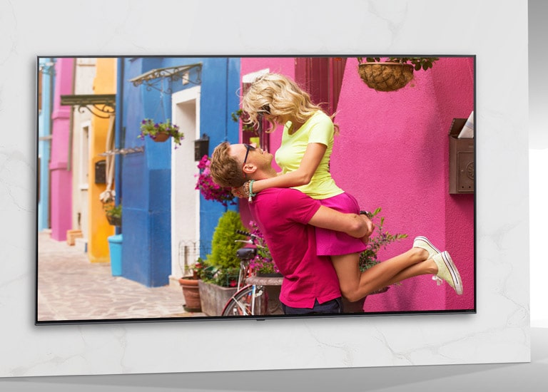 TV ekrane rodoma spalvingo romantinio filmo scena su apsikabinusiais vyrais ir moterimis