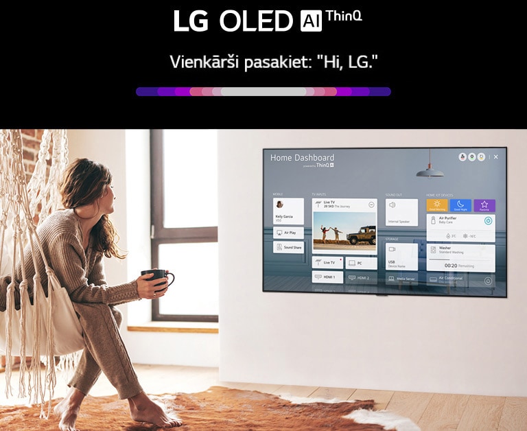 Svetainėje ant kėdės sėdinti moteris, TV ekrane rodomas namų skydelis