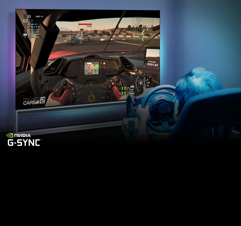 Vyras sėdi lenktynių žaidimų kėdėje, laiko lenktyninio automobilio vairą ir žaidžia lenktynių žaidimą TV ekrane