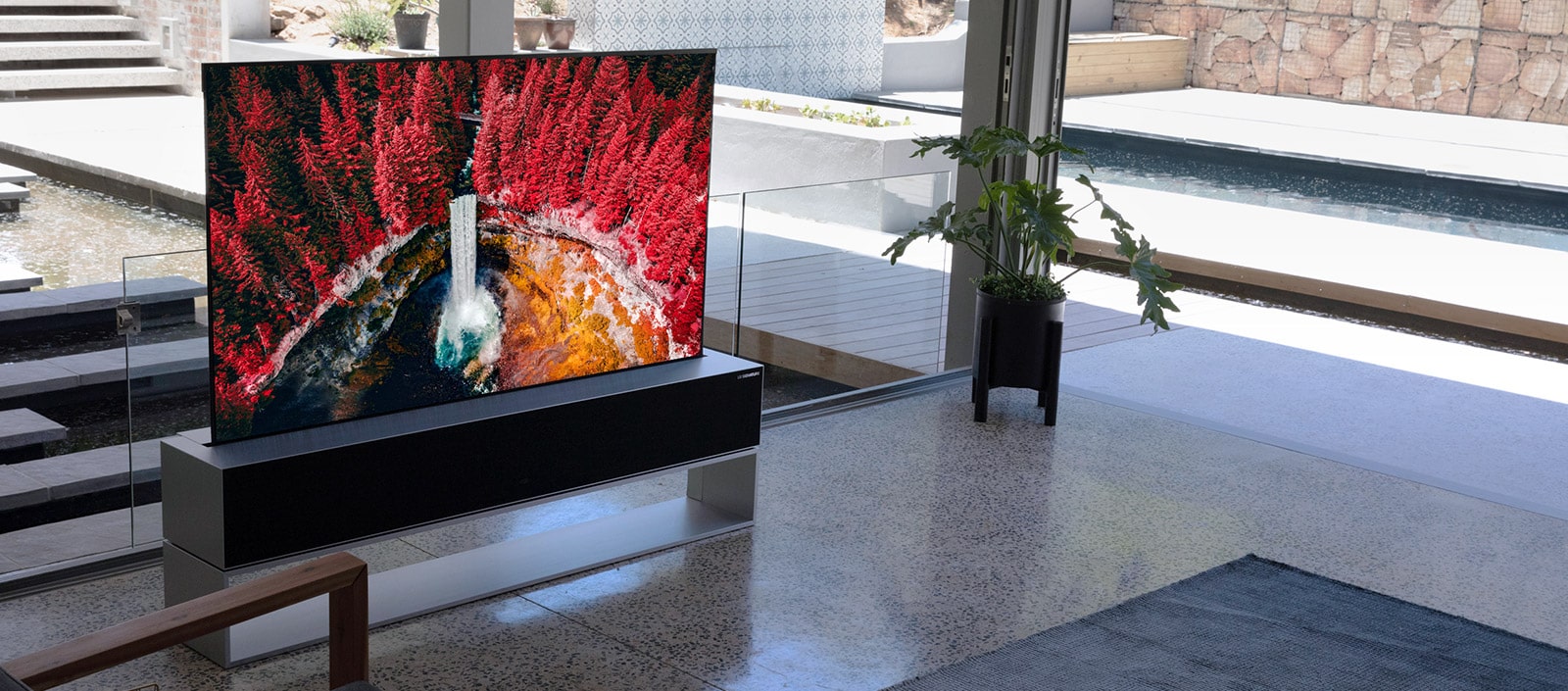 Prabangi svetainė su televizoriumi, kuriame vaizduojamas iš aukštai nufilmuotas peizažas