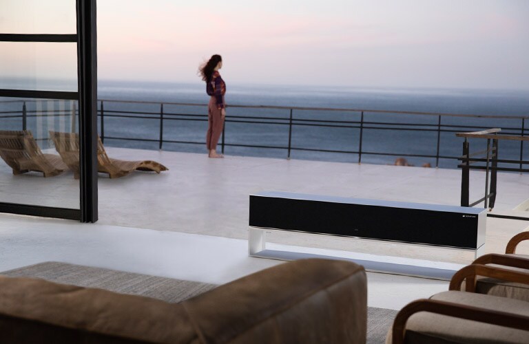 Prabangi svetainė, kurioje stovi moteris, yra sofa ir televizorius, veikiantis naudojant parinktį „zero view“