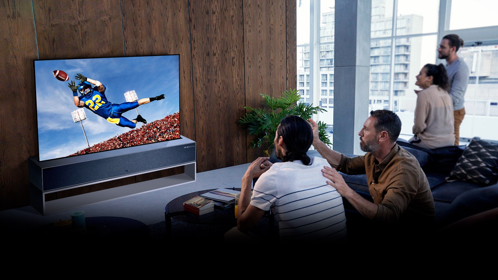 Žmonės svetainėje per TV žiūri amerikietiškojo futbolo rungtynes