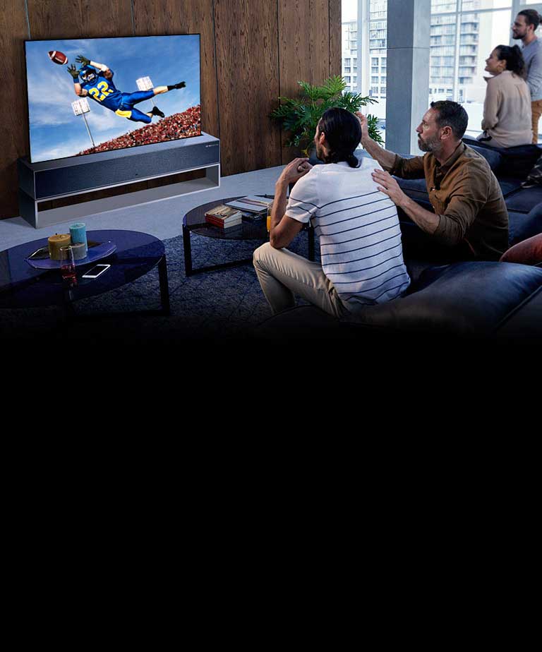 Žmonės svetainėje per TV žiūri amerikietiškojo futbolo rungtynes