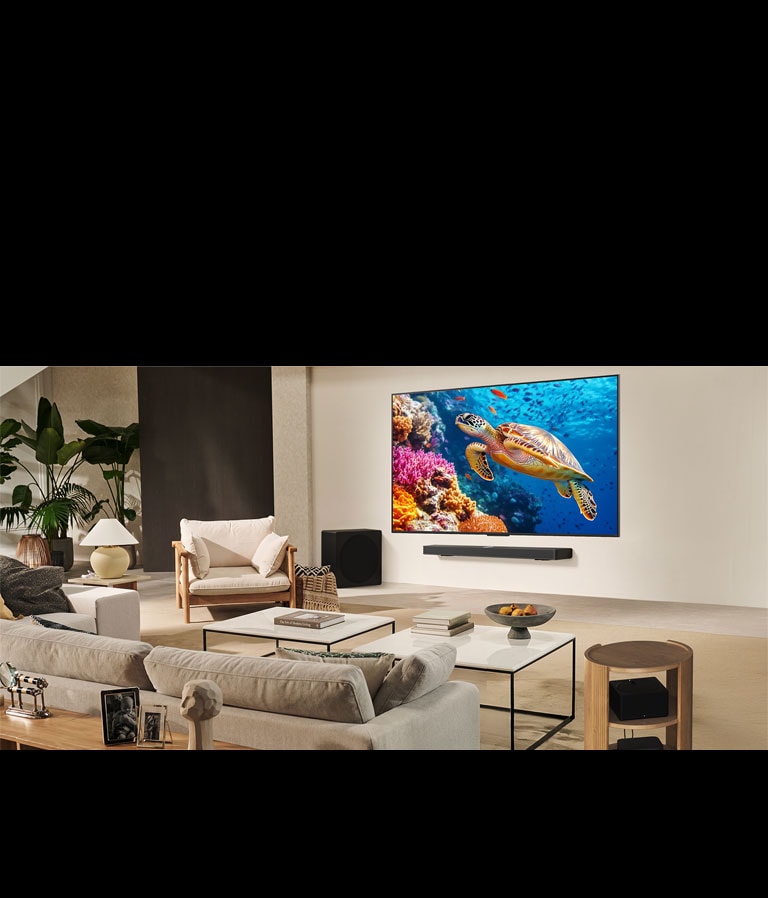 Šeima sėdi ant sofos priešais LG TV, sumontuotą ant sienos virš „LG Soundbar“. „Zero Connect Box“ yra kavos staliuko viduje.