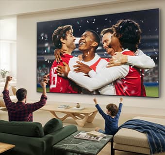 „LG QNED evo AI Mini LED QNED90“ itin didelis „Ultra Big“ TV rodo ryškių spalvų pergalės sceną stadione, o šeima kartu skanduoja nuo sofos gyvenamajame kambaryje.