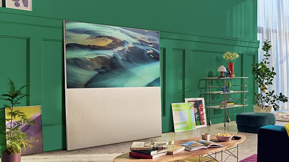 EASEL „Full View“ režimu, atremtas į žalios svetainės sieną ir apsuptas meno kūrinių. Ekrane rodomas smėlio kopų vaizdas.