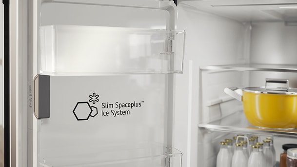 LG ledus sistēmas Slim SpacePlus™ Ice System uzlīme, kas redzama uz caurspīdīgā nodalījuma ledusskapja iekšpusē, blakus pudelēm un katlam.