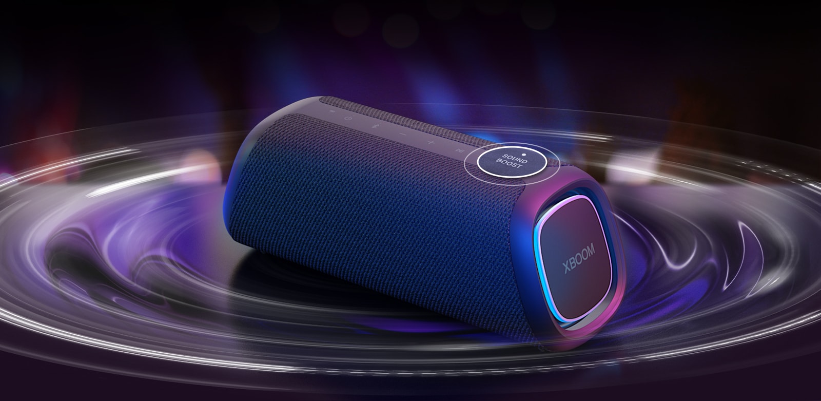 LG XBOOM GO XG7 ir novietots uz galda. Poga Sound Boost ir palielināta, un skaņas viļņu efekti atrodas zem skaļruņa. Atskaņojiet video.