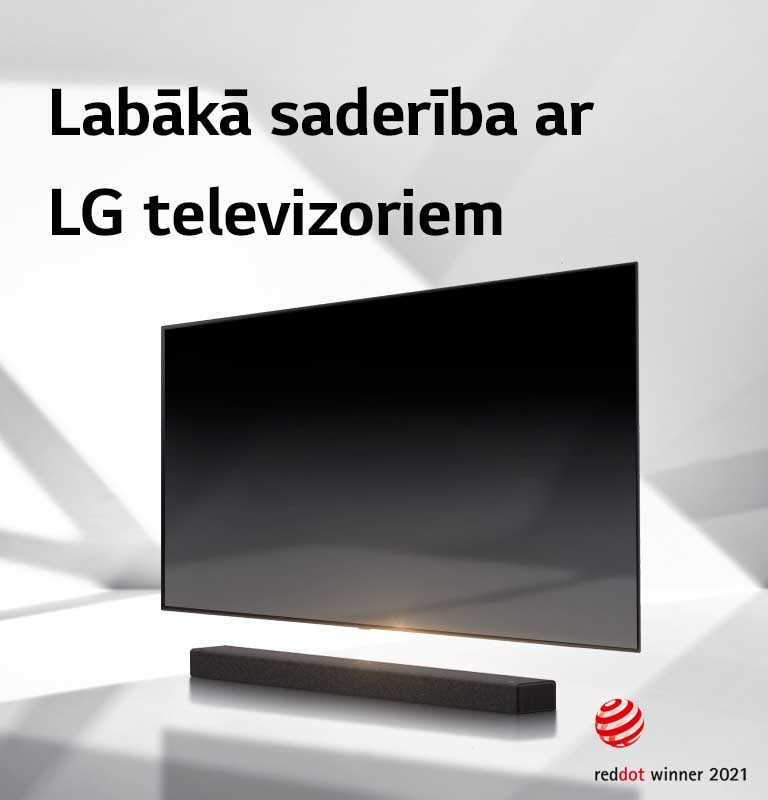 Skaņas josla un televizors novietoti uz baltas grīdas, un no ārpuses aiz tiem stiepjas ēna.