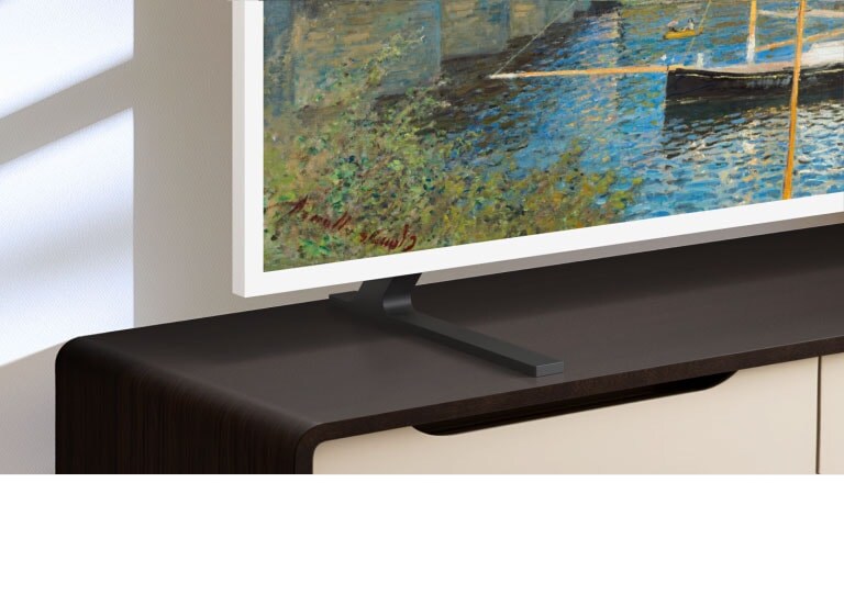 LG Gallery TV AI with frame LX7 ART TV ar augstumā regulējamo statīvu novietots uz multivides konsoles, statīvam pārvietojoties uz augšu un uz leju, tādējādi ļaujot elastīgi pozicionēt ekrānu dažādiem istabas izkārtojumiem un skatīšanās preferencēm.