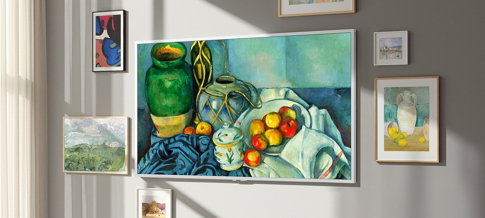 LG Gallery TV AI with frame LX7 ART TV ar galerijas dizaina ekrānu piestiprināts pie sienas ar klusās dabas gleznu displejā. Tas novietots pie loga ar citiem ierāmētiem mākslas darbiem, un, neskatoties uz saules gaismu, tā ekrānā nav redzamu atspulgu, liekot tam izskatīties kā īstam mākslas darbam.
