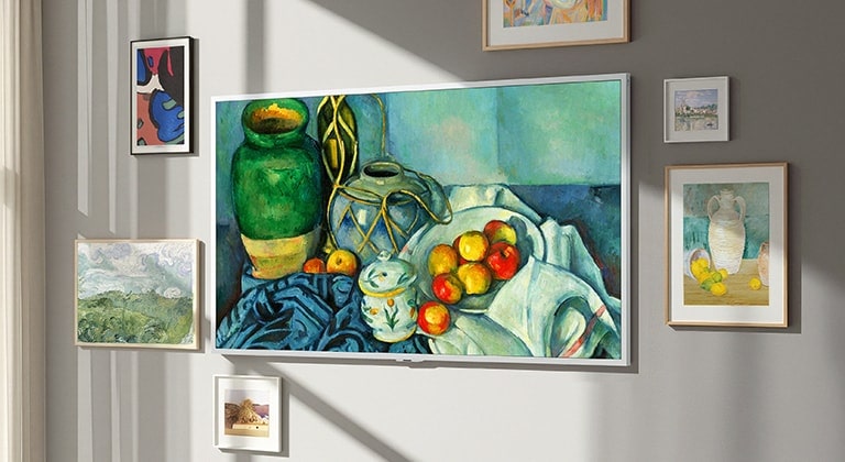 LG Gallery TV AI with frame LX7 ART TV ar galerijas dizaina ekrānu piestiprināts pie sienas ar klusās dabas gleznu displejā. Tas novietots pie loga ar citiem ierāmētiem mākslas darbiem, un, neskatoties uz saules gaismu, tā ekrānā nav redzamu atspulgu, liekot tam izskatīties kā īstam mākslas darbam.