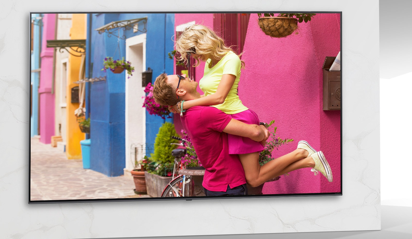 Lo schermo TV mostra una scena di un colorato film romantico in cui uomini e donne si coccolano.
