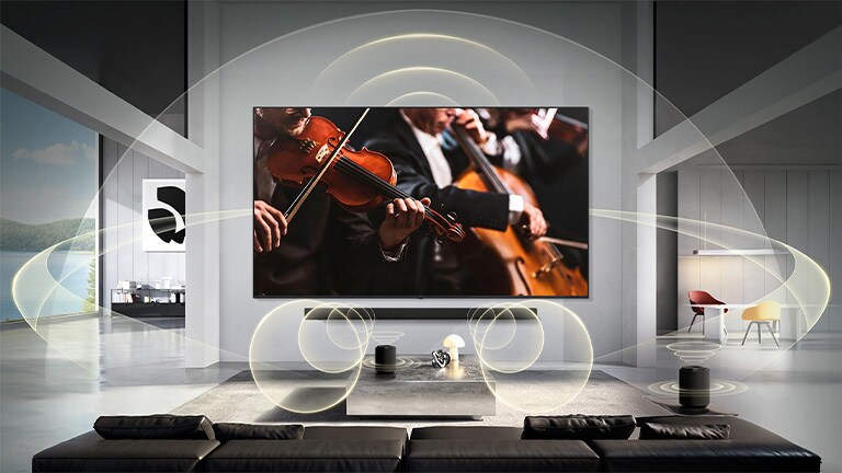 LG Mini RGB evo AI MRGB85 ar WOW Orchestra rāda koncerta ainu ar Soundbar zem ekrāna, savukārt grafiski attēloti skaņas viļņi izplatās pa viesistabas telpu, nododot sinhronizētu telpisko skaņu.