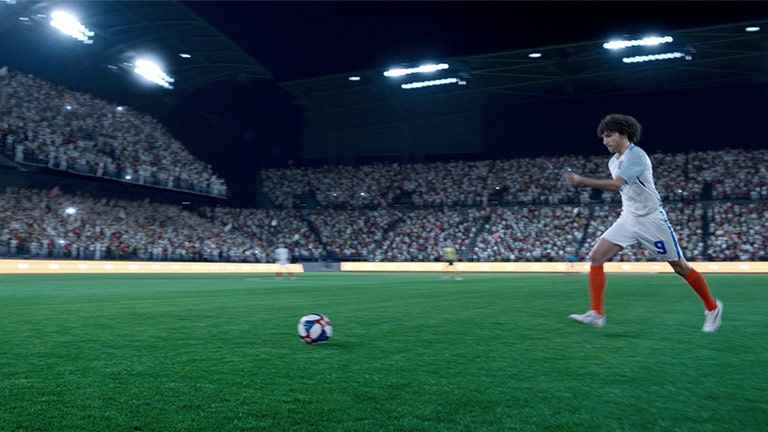 Vīrietis sēž dīvānā un ir iegrimis futbola spēles vērošanā. Skatīšanās laikā atnāk draugi, un viņi skatās kopā. Redzams logotips “Kļūstiet par superzvaigzni, izgaismojiet spēli”