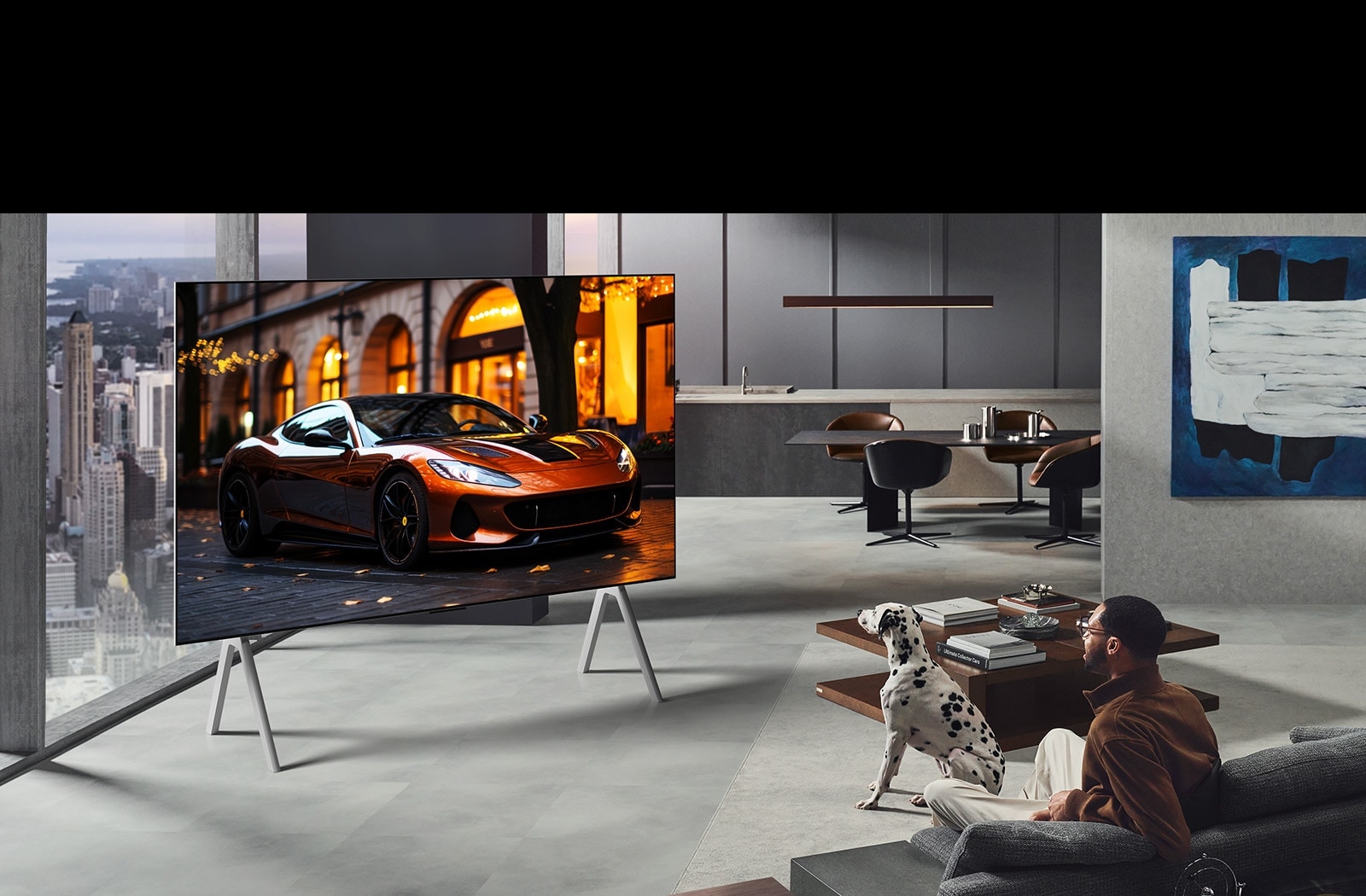 Dzīvojamā istaba ar LG True Wireless TV uz statīva. Zero Connect Box zem sānu galdiņa pie dīvāna gandrīz nevar saskatīt, parādot, ka to var ērti novietot jebkur. Viss istabas izkārtojums ir skaits un kārtīgs.