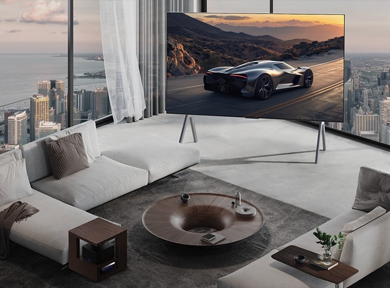 Plaša viesistaba ar skatu uz pilsētas ainavu. LG OLED TV ir novietots uz statīva. Ultra Slim dizains rada ekrānam iespaidīgu sajūtu.  Zero Connect Box ir redzams, bet paslēpts.