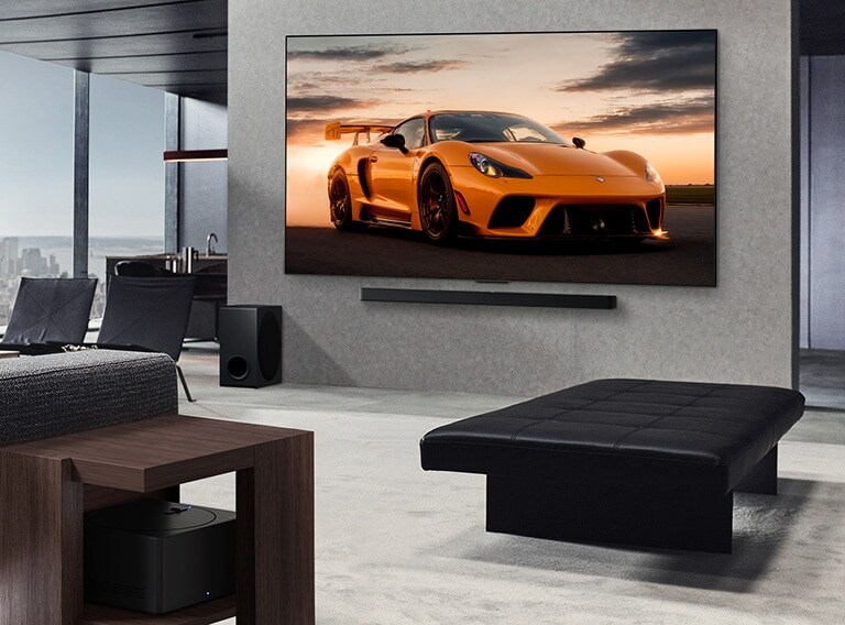 Plaša viesistaba ar skatu uz pilsētas ainavu. LG OLED TV ir piestiprināts pie sienas un LG Soundbar. Tiek demonstrēts TV Ultra Slim dizains. Zero Connect Box ir redzams, bet paslēpts.